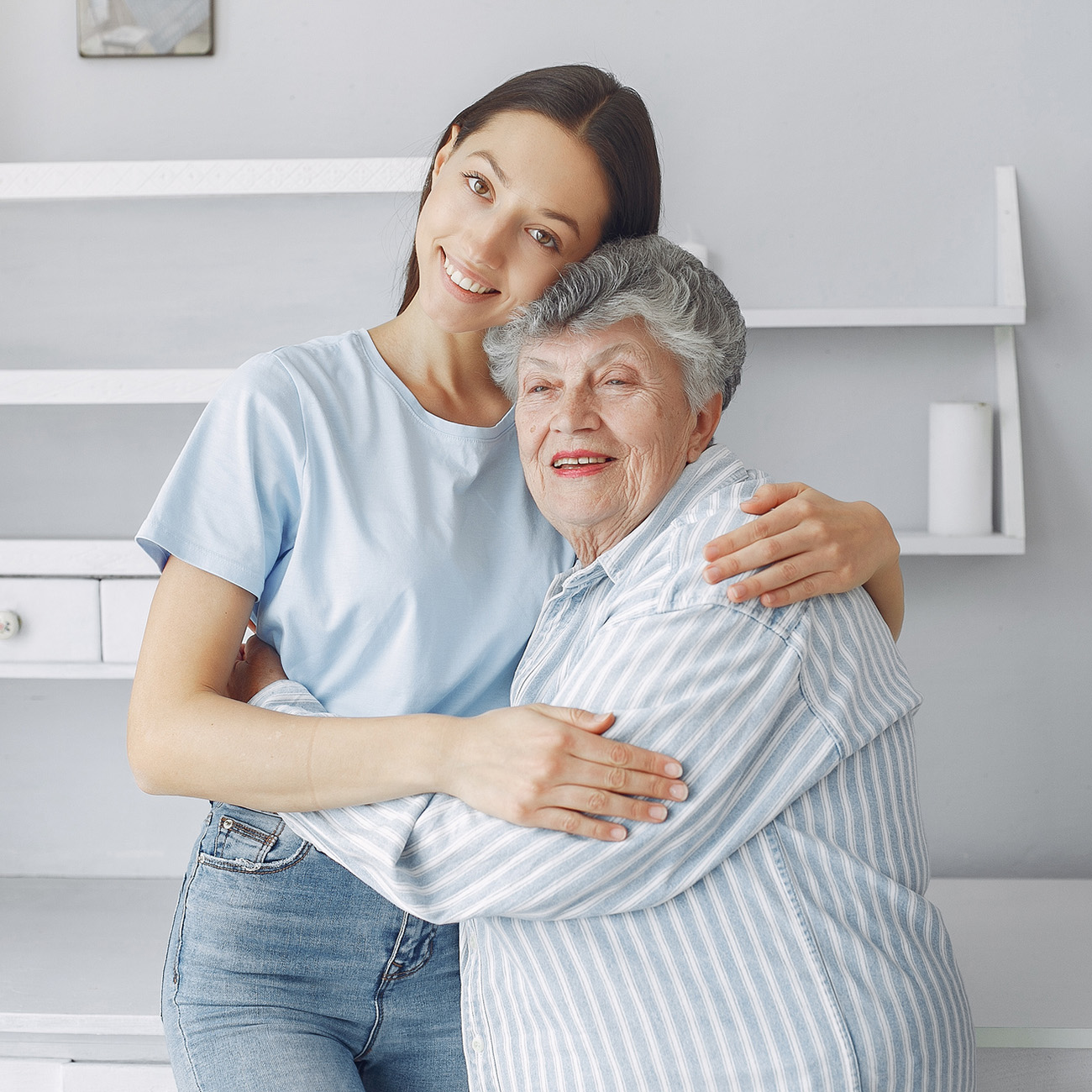 Elderly mother and young daughter standing in their living room smiling